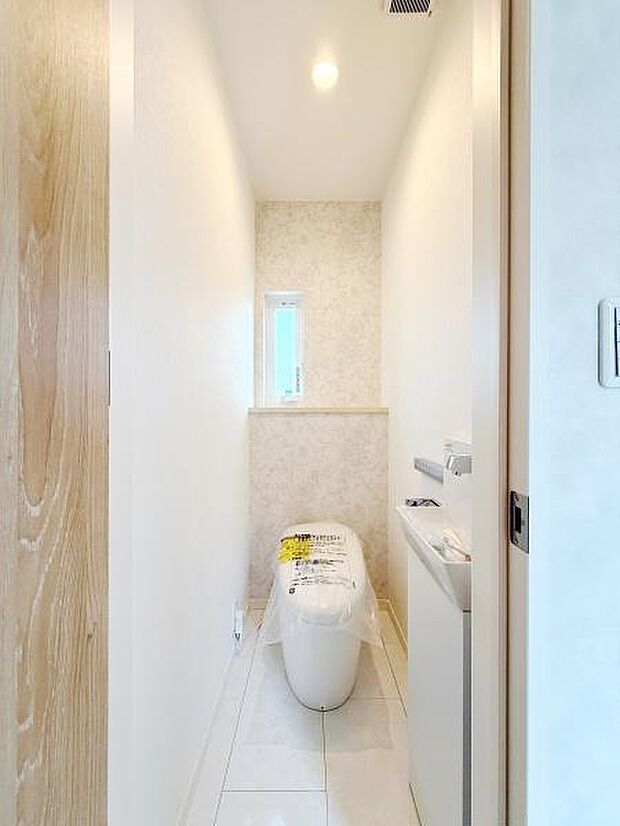 白を基調とした明るいトイレです。小窓が設置されており自然光が入ります。コンパクトながらも清潔感のある空間です。ゆったり使える奥行きのあるレイアウトです。収納スペースも用意されています。