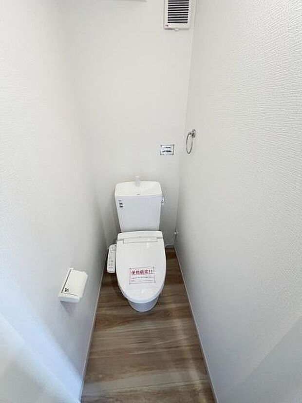 清潔感のあるトイレ空間です。シンプルな内装でお手入れしやすい仕様となっています。換気扇も設置されており快適な使い心地が期待できます。温水洗浄機能付きですっきりとした印象となっています。