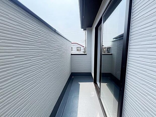 すっきりとしたデザインのバルコニーです。外壁と床の色合いが調和し清潔感があります。大きな窓から自然光がたっぷり入ります。高めの壁で周囲の視線が気になりにくい仕様です。日当たりも期待できる設計です。