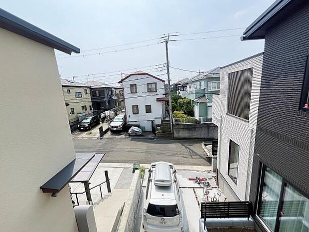 住宅街の雰囲気が伝わる一枚です。周囲には複数の戸建てが並び落ち着いた環境がうかがえます。車の駐車スペースがしっかりと確保されています。バルコニーや窓から外の様子を確認できる点もポイントです。