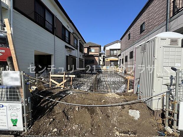 青空のもと建築中の住宅現場です。周囲は住宅街に囲まれており落ち着いた雰囲気が感じられます。整然とした区画で住まいのイメージがしやすい立地です。工事が進む様子が分かり未来の住まいへの期待が高まります。