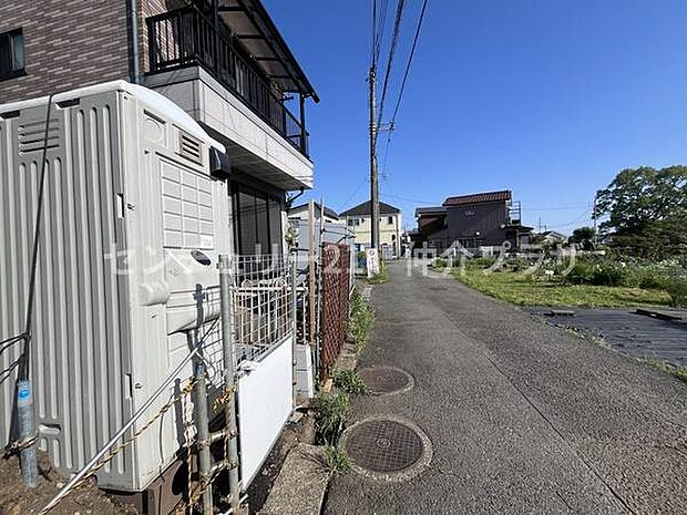 前面道路が広く車両の出し入れもスムーズに行えます。周辺に建物があり落ち着いた雰囲気が感じられます。晴れた日の空が広がる開放的なロケーションです。現地の状況が分かりやすく撮影されています。