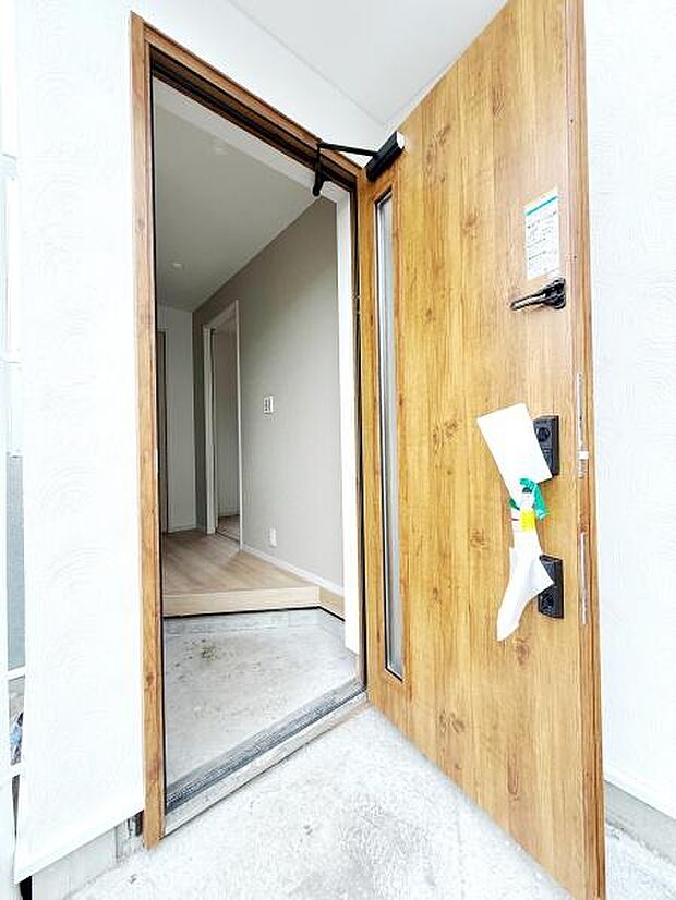 木目調の玄関ドアが印象的で温かみのある雰囲気を感じられます。ドアのサイドガラスからはやさしい光が入ります。室内へ自然につながる開放的なエントランスが魅力です。