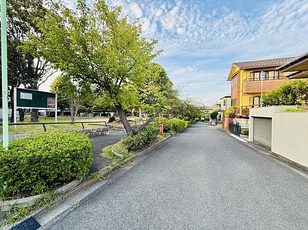 緑豊かな街並みが広がるエリアです。道路沿いには公園もあり落ち着いた雰囲気が感じられます。周囲の住宅も整っていて住環境が整っています。青空と木々が爽やかな印象を与えます。