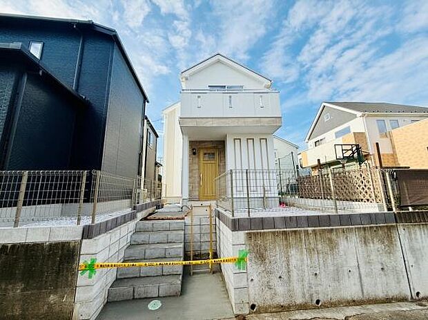 白を基調とした明るい外観が印象的です。門扉から玄関までのアプローチがしっかりと整備されています。前面道路からの段差がありプライバシーにも配慮されています。バルコニーが2階にあり採光も期待できます。