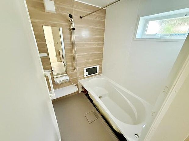 木目調のアクセントパネルが印象的なバスルームです。大きな鏡と窓があり室内に明るさを取り入れています。