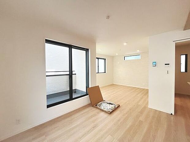 大きな窓から光がたっぷり入るリビングです。シンプルな内装が空間を広く見せています。明るい木目の床がすっきりとした印象を与えます。バルコニーへのアクセスも可能です。