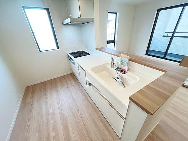 明るい日差しが入るキッチンは開放感のある空間です。窓が多く通風も良好です。収納も豊富で整理しやすい設計となっています。カウンターの木目調がアクセントになっています。清潔感と機能性を兼ね備えています。