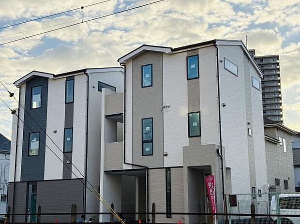 前面道路に面した現地写真です。道幅が広く開放感のある立地です。建物の工事が進行中の様子がわかりやすい写真です。