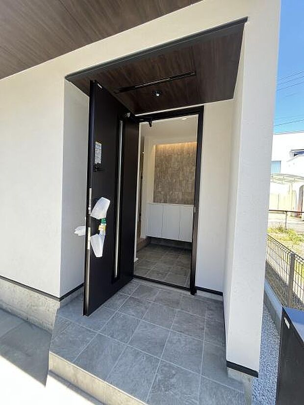 明るく広がりのある玄関スペースが魅力です。シンプルなタイル仕上げが落ち着いた雰囲気を演出しています。玄関収納も備えておりすっきりとした空間です。ダークカラーの扉がアクセントになっています。