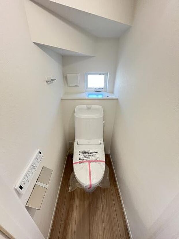 コンパクトなスペースに配置されたトイレです。手が届きやすい位置にペーパーホルダーとリモコンが設置されています。小窓が設けられており換気や採光に役立ちます。