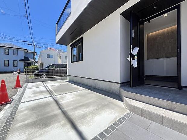 建物の外観がスタイリッシュな印象を与えます。玄関アプローチがゆったりとした設計です。駐車スペースには車の出入りがしやすい配置となっています。前面道路も広めで視界が良好です。