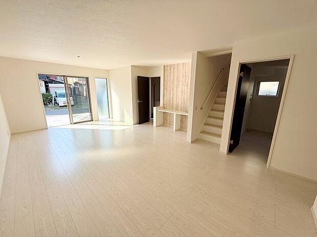 大きな窓からたっぷりと自然光が差し込むリビングです。白を基調とした床と壁で空間を広く感じられます。階段脇にはカウンタースペースがあり使い勝手が良さそうです。出入口も複数あり動線がスムーズです。