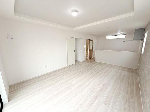 リビング全体が明るく広がりを感じられる空間です。白を基調としたシンプルな内装でインテリアの配置も楽しめます。天井のデザインが部屋にアクセントを加えています。床材の色合いもやわらかく清潔感があります。