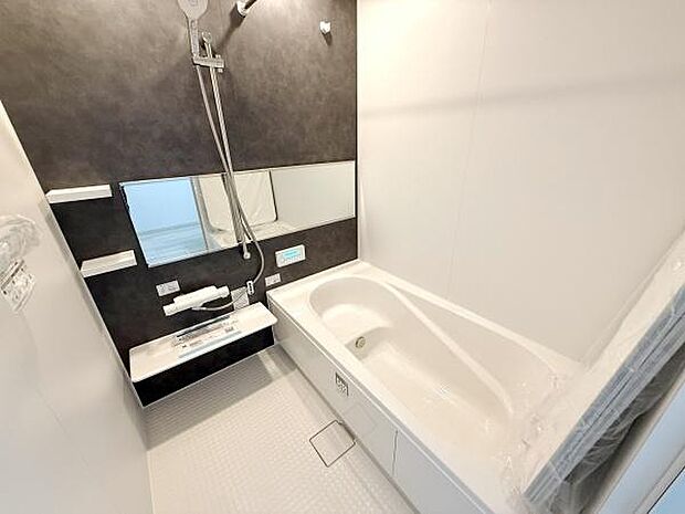 清潔感のあるバスルームです。壁面に設置された鏡が空間を広く見せてくれます。シンプルなデザインで使いやすい仕様です。床には滑りにくい素材が使われており安全面も考慮されています。