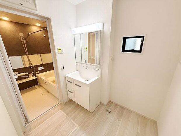 洗面台・洗面所は清潔感のある空間となっています。明るい照明が手元をしっかり照らします。洗面台横の収納スペースも便利です。浴室への動線もスムーズです。手入れがしやすい床材が採用されています。