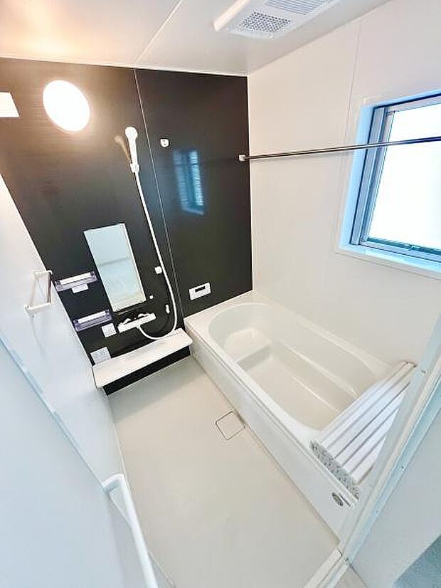 光が差し込む窓付きのバスルームです。シンプルながらも落ち着いた色合いの壁がアクセントになっています。浴室乾燥機が天井に設置されており利便性に配慮されています。