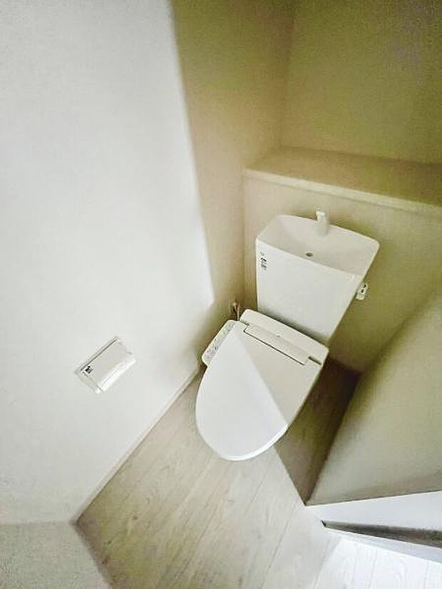 清潔感のある明るいトイレ空間です。落ち着いた色合いの内装が印象的です。温水洗浄便座が備え付けられています。ペーパーホルダーやタオルリングの設置で使い勝手も考慮されています。