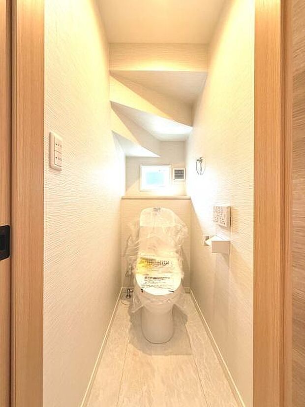 明るい色調の内装で清潔感が際立つトイレです。小窓があるため換気がしやすく快適な空間となっています。壁面に収納スペースも備わっており日用品の管理もしやすい設計です。