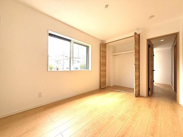 クローゼットが備え付けられた明るい室内です。収納スペースが広くすっきりと整理しやすい設計です。無駄のないシンプルな空間で使い勝手にも配慮されています。床や扉の木目調が落ち着いた印象を与えます。