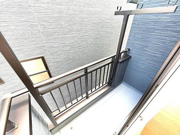 室内からの動線がスムーズなバルコニーです。シンプルな手すりで開放感があります。洗濯物干しスペースに便利な設備が整っています。周囲の壁も落ち着いた色合いで統一されています。