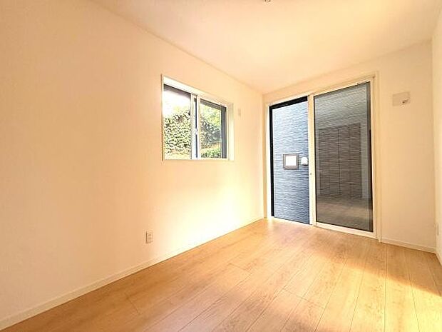 大きな窓とガラス扉から自然光がしっかり入る洋室です。明るく開放感のある空間が広がります。壁や床はシンプルなデザインなので家具選びも自由です。清潔感のある雰囲気が魅力のひとつです。