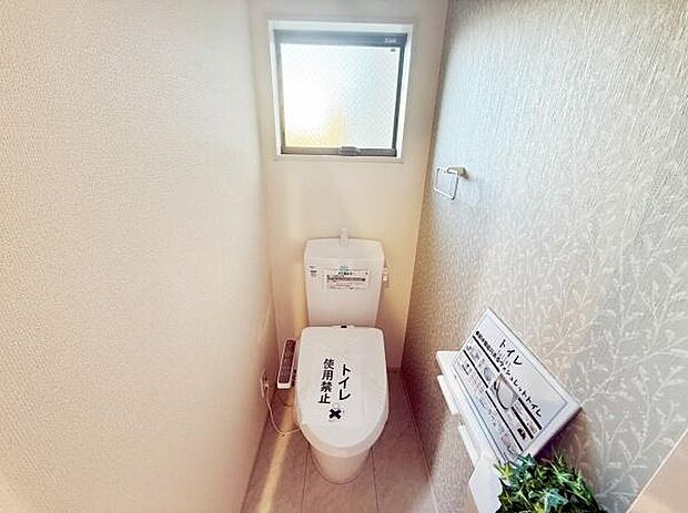 トイレには窓があり自然光が差し込む明るい空間です。壁のデザインもポイントになっています。設備の配置がシンプルで使いやすい印象です。トイレ周りもすっきりと整理されています。