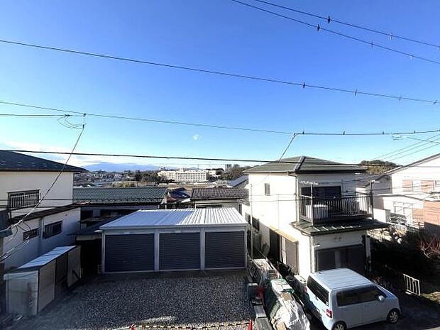 晴れた空が広がる現地からの眺望です。周囲には住宅が並び穏やかな街並みが特徴的です。遠くには山並みも見え奥行きのある景色を楽しめます。開放感のある見晴らしが魅力です。