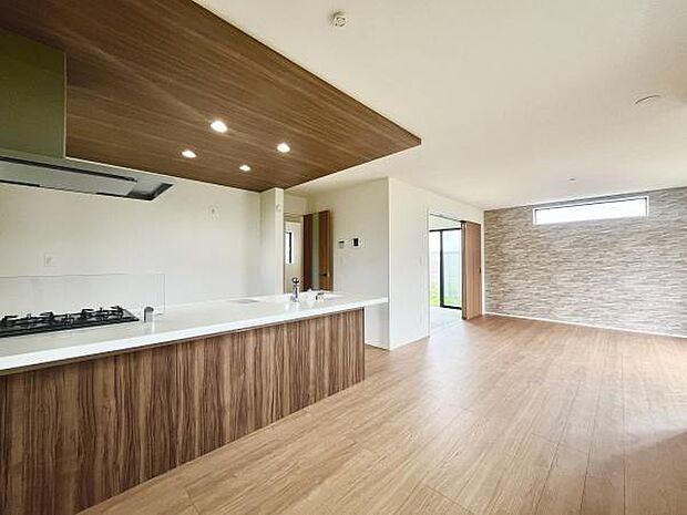 木目調のフローリングが空間に落ち着いた雰囲気を与えています。大きな窓から光が差し込み室内が明るく感じられます。キッチンとリビングがつながったレイアウトで開放感があります。