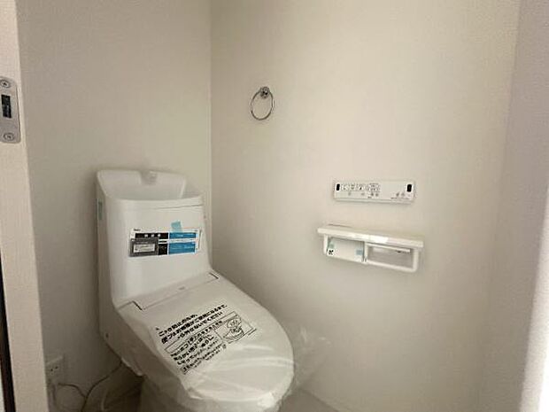 シンプルなデザインのトイレです。壁付けのリモコンで操作もしやすい仕様です。ペーパーホルダーが使いやすい位置に配置されています。清潔感のある空間が広がっています。