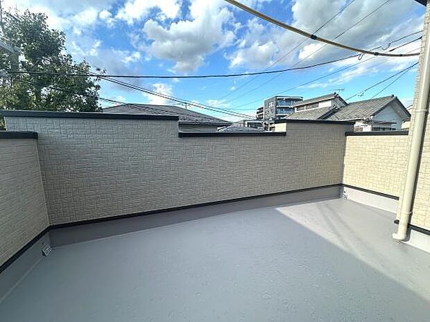 広々としたスペースが確保されたバルコニーです。高めの壁が外部からの視線を遮りプライバシーに配慮されています。空の景色を楽しめる開放感も魅力です。シンプルな設計でお手入れも簡単です。