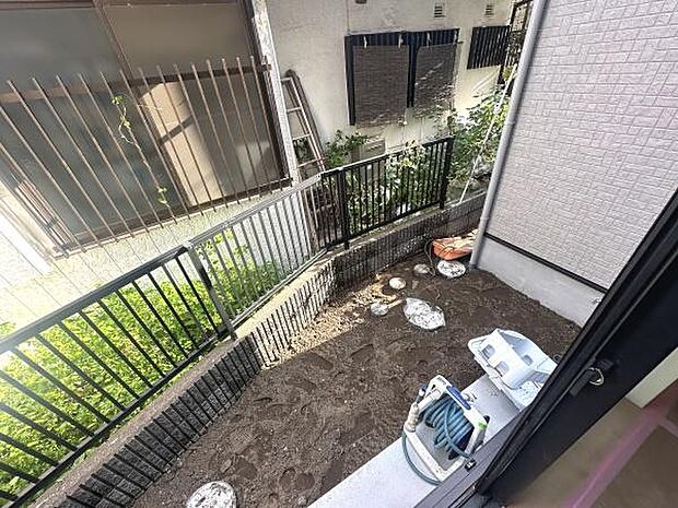 柵付きの専用庭スペースがありプライベートな空間として利用できます。日当たりも確保され管理も容易なサイズ感です。室外機や散水ホースも設置されており実用性も備えています。