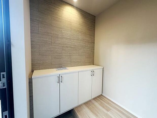 玄関はナチュラルな木目調の壁が特長的です。明るい色合いのフローリングと収納が空間をすっきりと見せます。収納スペースが十分に確保されています。照明もポイントとなる玄関です。