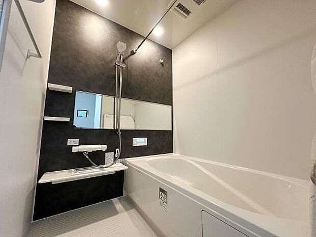 シンプルなデザインのバスルームでお手入れがしやすい仕様です。広々とした浴槽があり使い勝手のよい空間です。大きな鏡とシャワースペースが設けられています。清潔感のある色合いが印象的です。