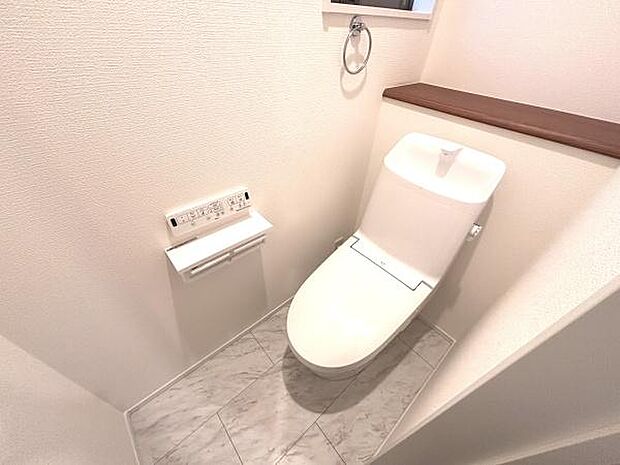 落ち着いた色合いの壁とフローリングで清潔感があります。トイレ本体もシンプルなデザインです。手洗い一体型で省スペースにまとまっています。ペーパーホルダーやリモコンが壁付けで使い勝手にも配慮されています。