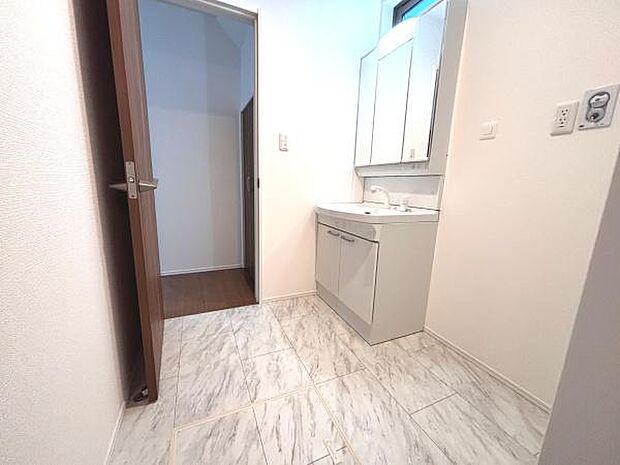 清潔感のある洗面台と無駄のないシンプルな空間が魅力です。明るい色調の床が室内を広々と見せます。収納スペースのある洗面台で日々の使い勝手も良好です。開閉しやすいドアで移動もスムーズです。