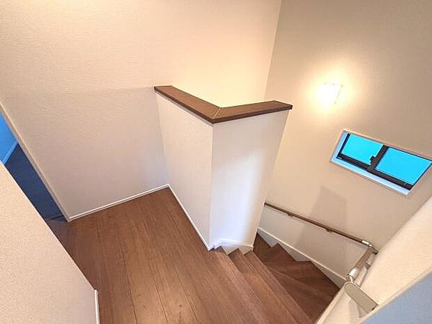 階段部分に手すりが設置されており安心して上り下りできます。小窓から自然光が入るため明るい空間です。壁や床材の色味が落ち着いた雰囲気を演出しています。