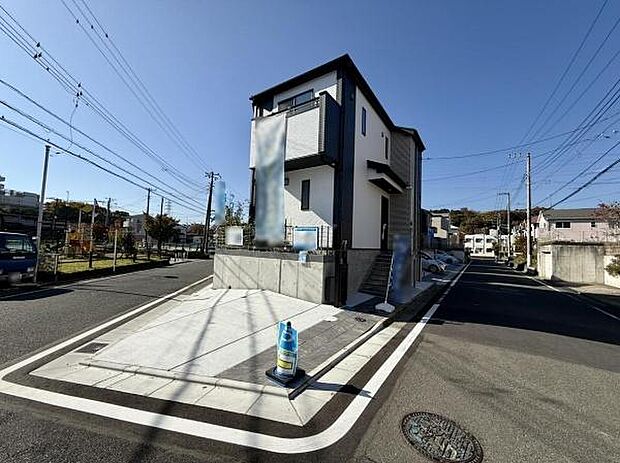 1号棟 前面道路が広く車の出し入れがしやすい立地です。角地に位置し開放感のある現地写真です。建物外観がスタイリッシュで目を引きます。周囲には住宅が並び落ち着いた雰囲気です。