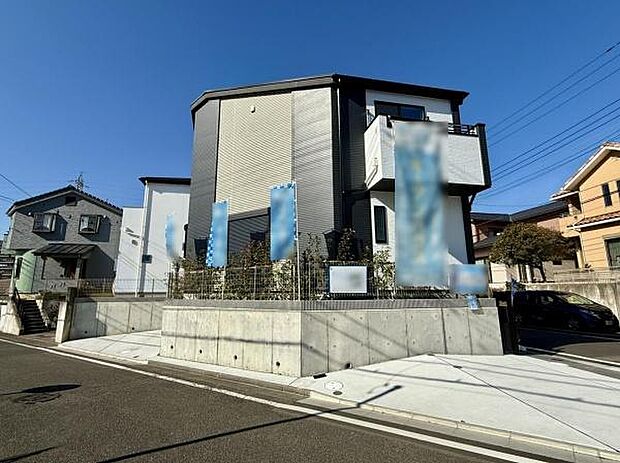 1号棟 シンプルでスタイリッシュな外観が目を引きます。高台に建つことで通りからの視線を程よく遮ります。前面道路も広々としていて出入りがしやすい立地です。隣接する建物と適度な距離感が保たれています。