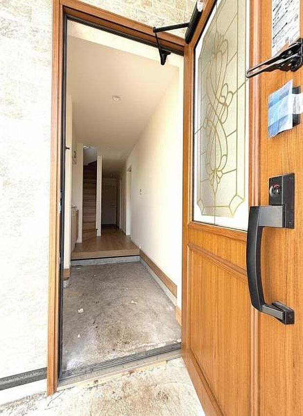 玄関部分はゆとりのあるスペースが確保されています。木目調の扉が落ち着いた雰囲気を演出しています。室内への動線もスムーズです。明るい空間で出入りがしやすい造りです。