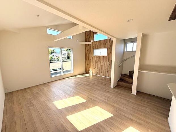 広々としたリビングは大きな窓から自然光がたっぷりと入ります。木目調のアクセントウォールが空間を引き締めます。天井の梁が開放感を演出しています。階段のデザインもシンプルで使いやすい印象です。