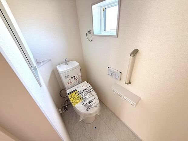 窓が設置されたトイレは明るい空間を実現しています。手すりが備わっており安心してご利用いただけます。清潔感のある内装です。ペーパーホルダーやリモコンも設置済みです。
