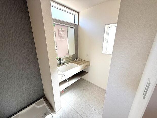 明るい光が差し込む洗面スペースです。窓があり換気に配慮された設計となっています。シンプルなデザインでお手入れも簡単です。収納棚も備えられており整理整頓しやすいです。