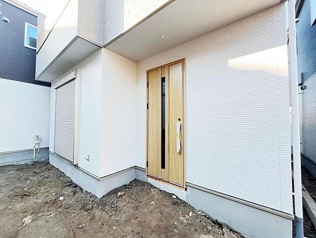 すっきりとしたデザインの玄関が住宅の印象を引き立てます。シンプルな外壁と木目調ドアが調和しスタイリッシュな雰囲気を演出しています。玄関スペースは出入りしやすい位置に配置されています。