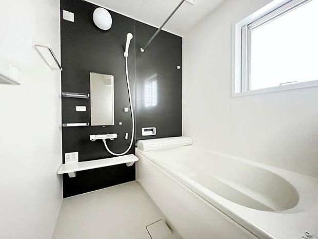 明るいバスルームはシンプルな配色で清潔感があります。浴槽はゆったりとしたサイズ感です。使いやすい洗い場スペースや便利な鏡と棚が設置されています。窓から自然光が差し込み開放感があります。