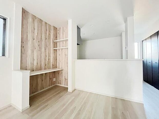 木目調のアクセントクロスが印象的な空間です。カウンターや棚がすっきりと設置されています。全体が明るい色合いで統一されているため清潔感があります。収納スペースも充実しています。窓からの採光も良好です。