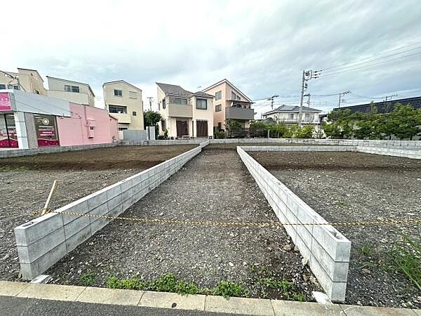 整形地で使いやすい区画が特徴的です。周囲には住宅や店舗があり生活利便性も感じられます。現況を活かした自由なプランニングが可能です。平坦な地形で建築計画も進めやすい現地土地写真です。