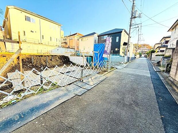 現地写真では周囲の住宅と調和した落ち着いた街並みが確認できます。前面道路は舗装されており見通しの良い直線道路です。現場周辺はすっきりとした印象で環境が整っています。