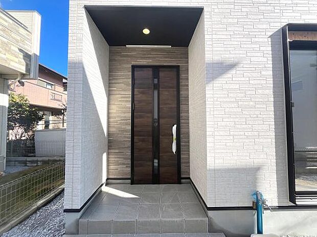 スタイリッシュなデザインの玄関が住まいに洗練された印象を与えます。シンプルな外壁と調和し落ち着いた雰囲気が魅力です。屋根付きのスペースが玄関先を雨や日差しから守ります。