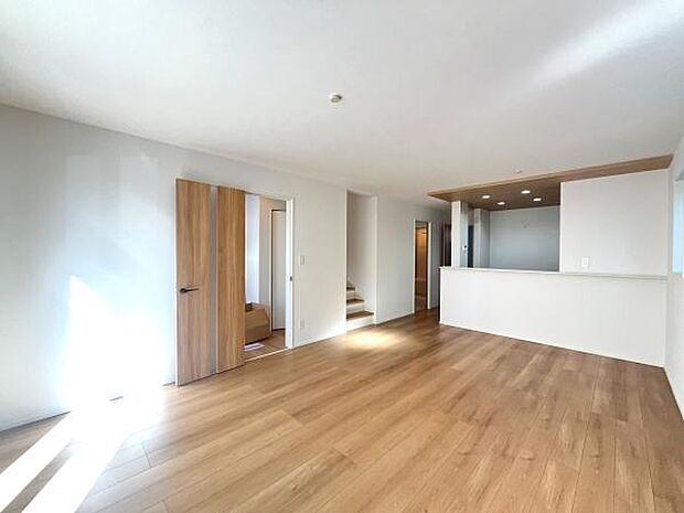 リビングは明るい日差しが差し込み心地よい空間が広がります。木目調の床が落ち着いた雰囲気を演出します。開放的な設計で家具の配置もしやすいです。ドアや階段の配置が生活動線を考慮したつくりです。